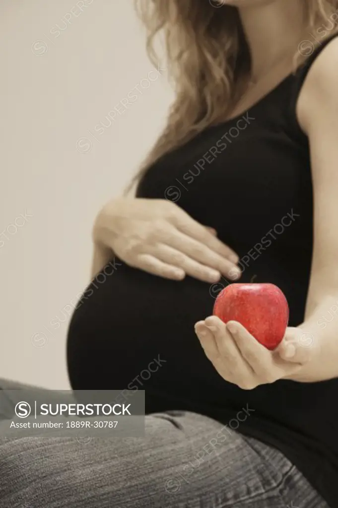 A pregnant woman holding apple