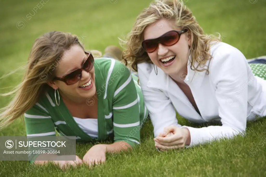 Two women wearing sunglasses and laughing
