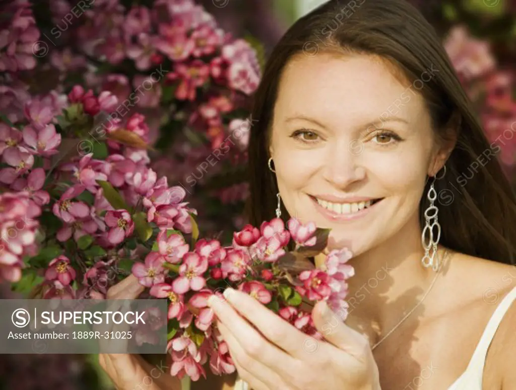 Young woman smiling and smelling flowers
