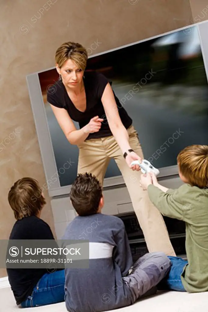 Woman stopping boys from playing video game