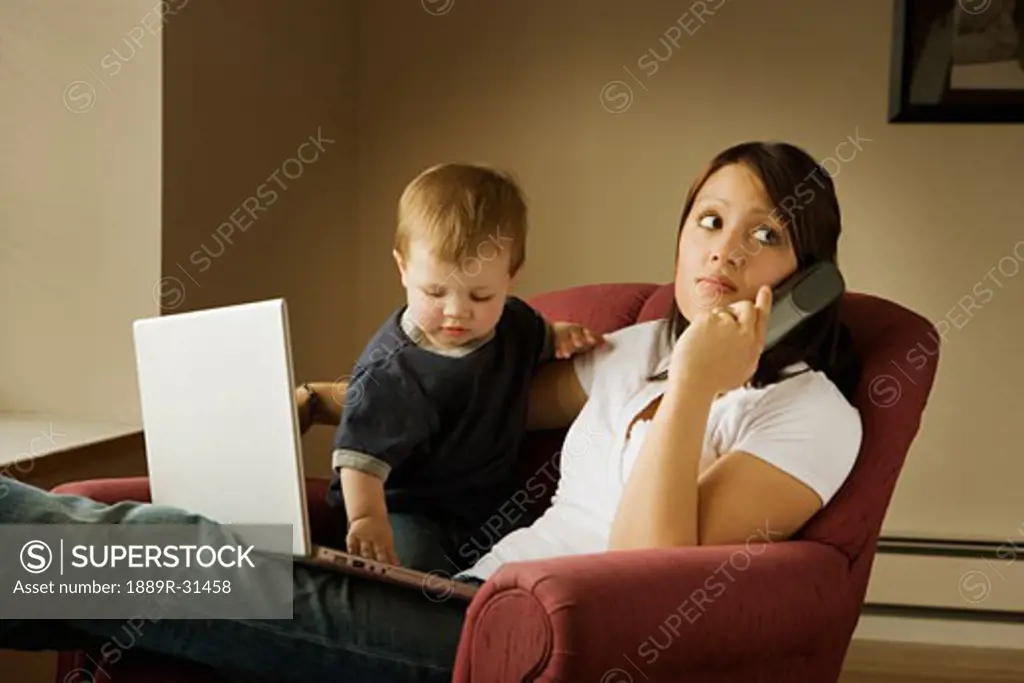 Mother on the phone with laptop and child on her lap