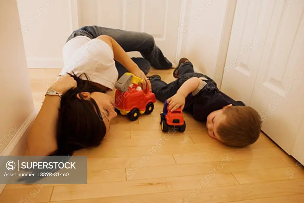 Mother and son laying on the floor playing with toys