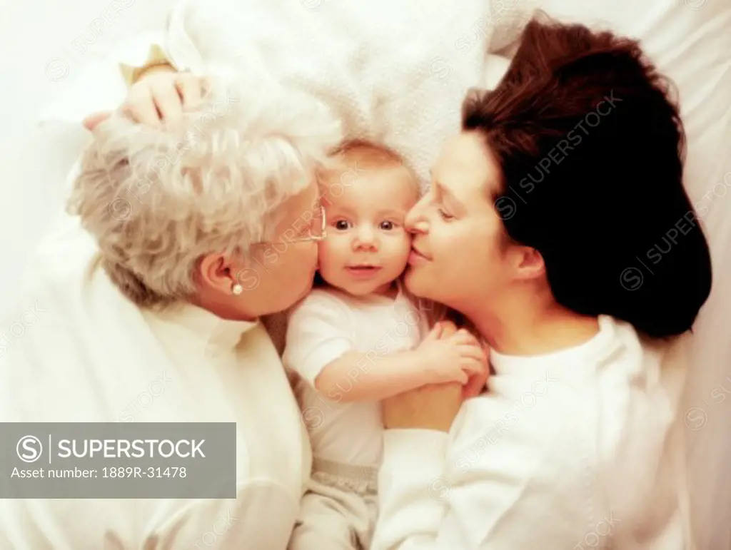 Mother and grandmother kissing baby