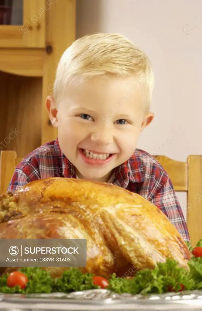 Boy with roast turkey at table  