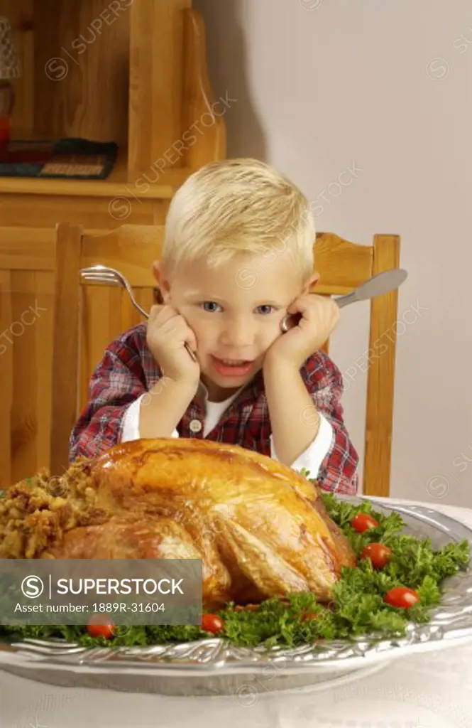 Boy with cooked turkey at table  