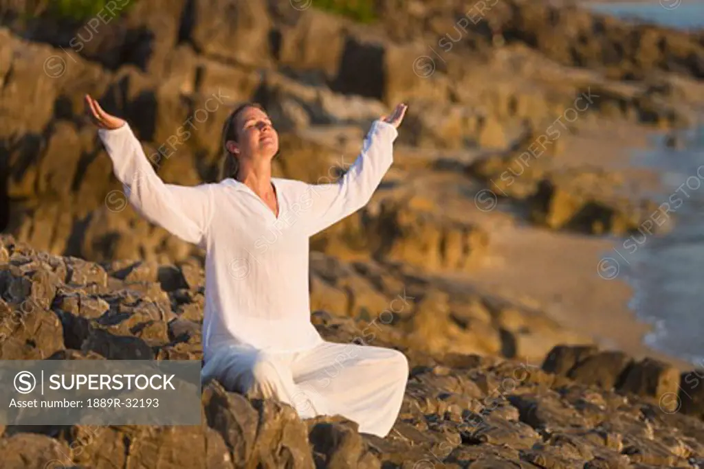 Woman worshipping on rocky shore