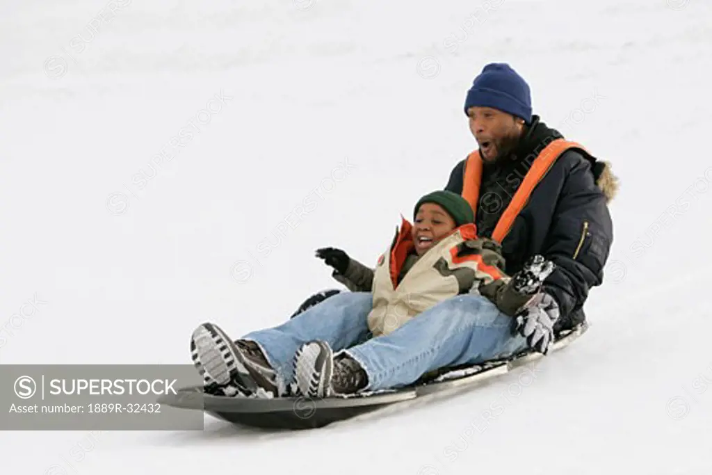 Father and son sledding on snow