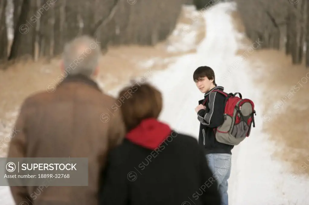 A teenage boy walking on a snow-covered path