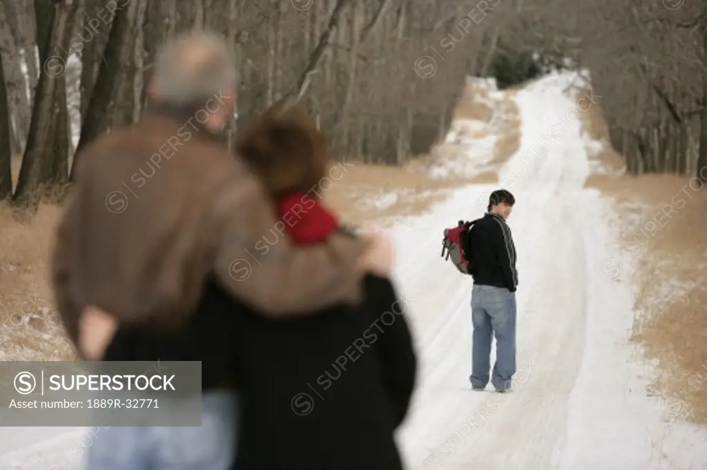 A teenage boy walking down a snow-covered path