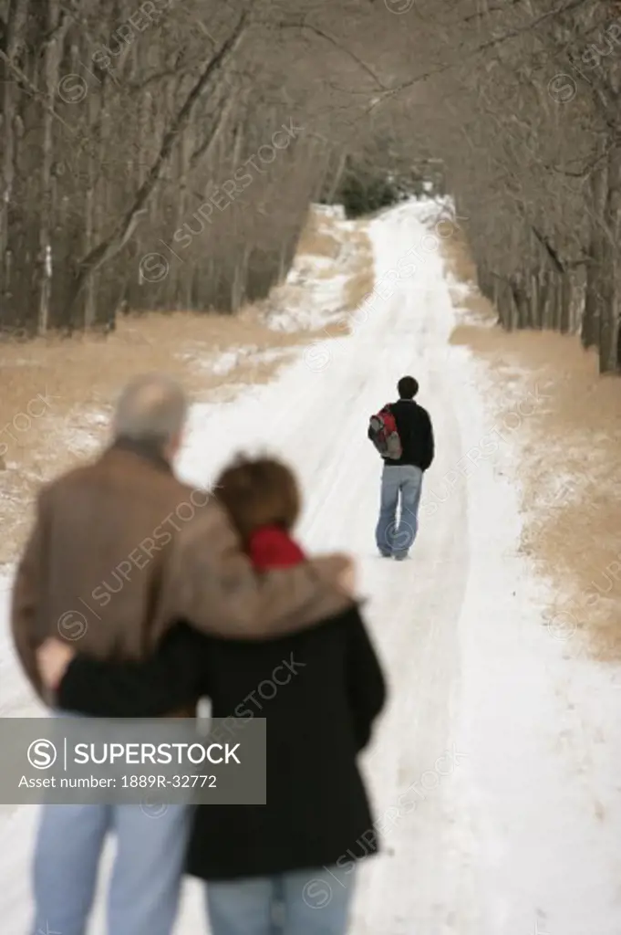 A teenage boy walking down a snow-covered path