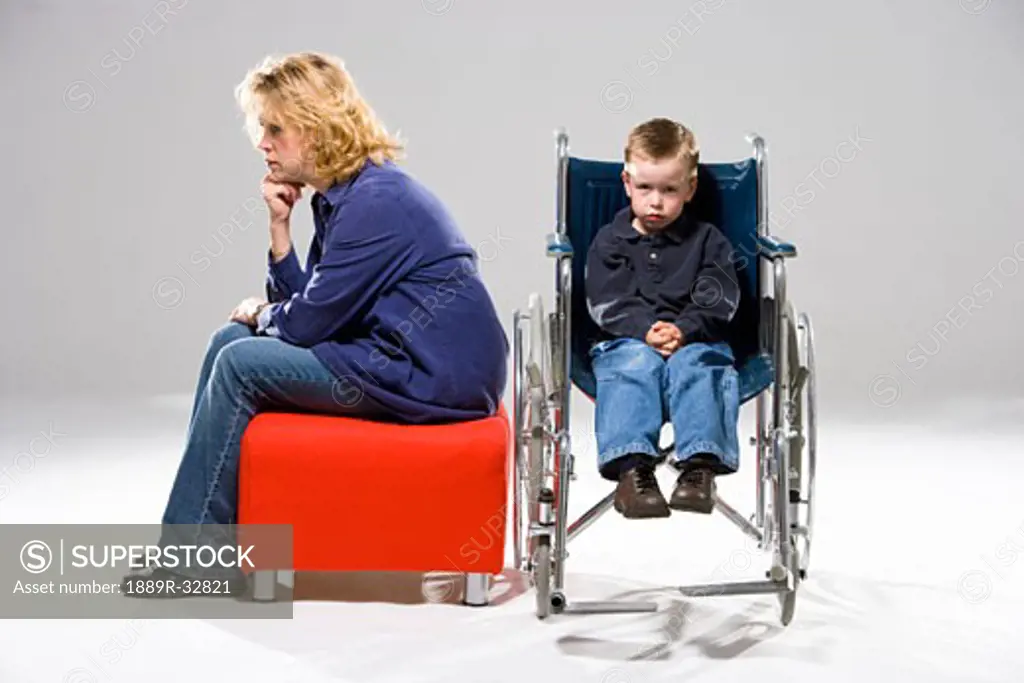 Child in wheelchair with mother sitting beside him