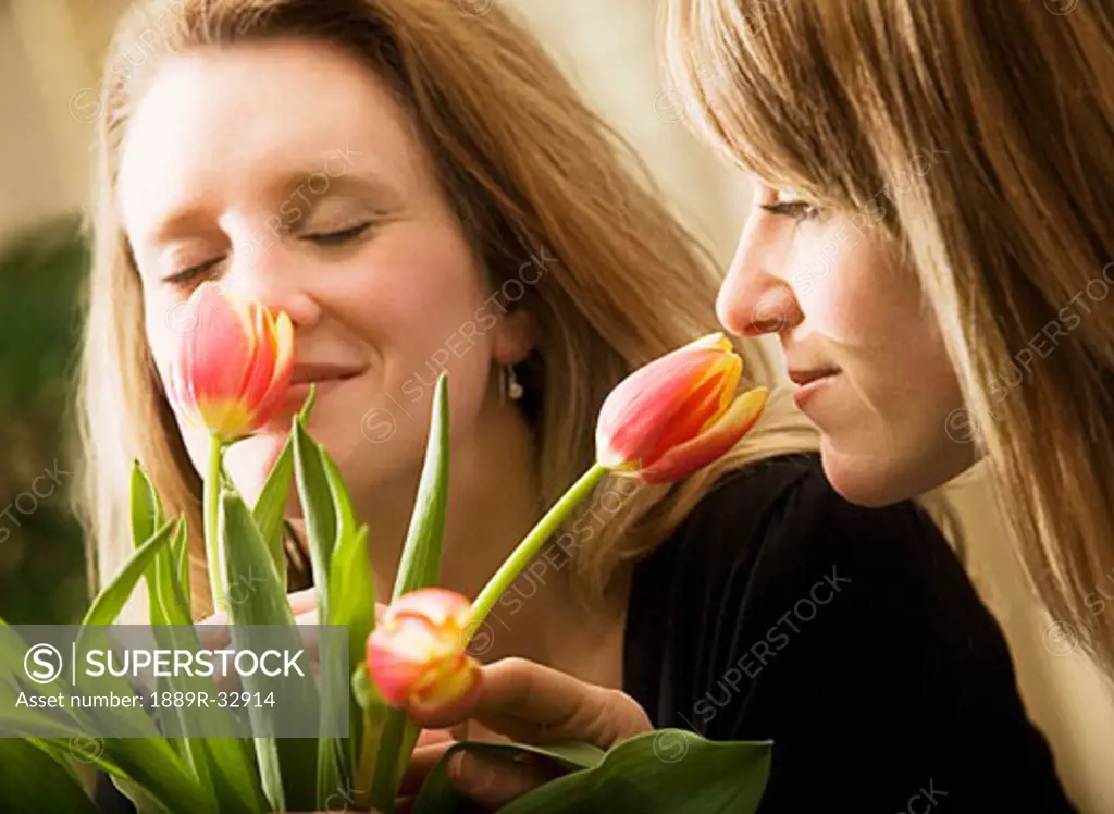Two women smelling flowers