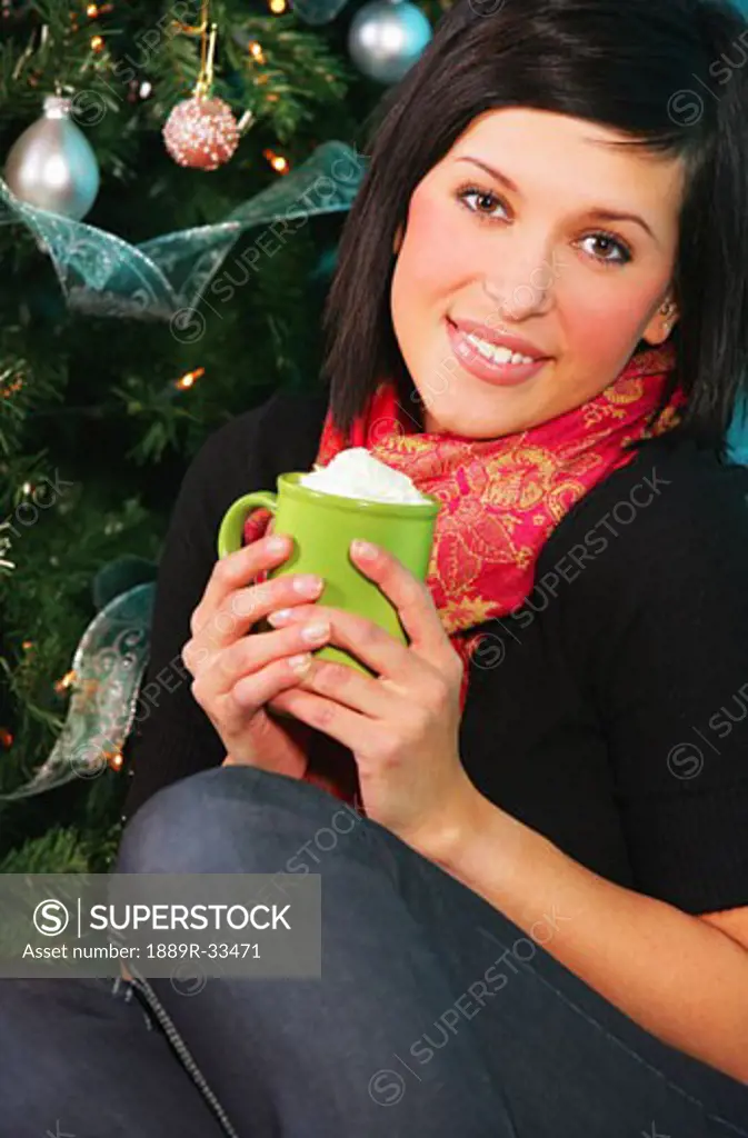 Woman with mug by Christmas tree
