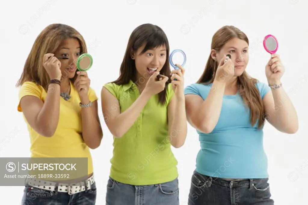 Three teens applying makeup