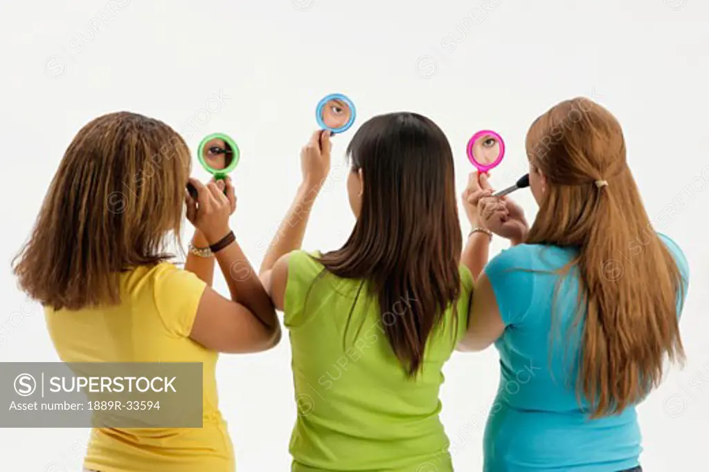Three teen girls with compact mirrors