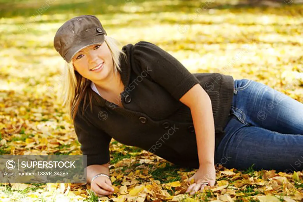 Teenage girl lying on in the fall leaves