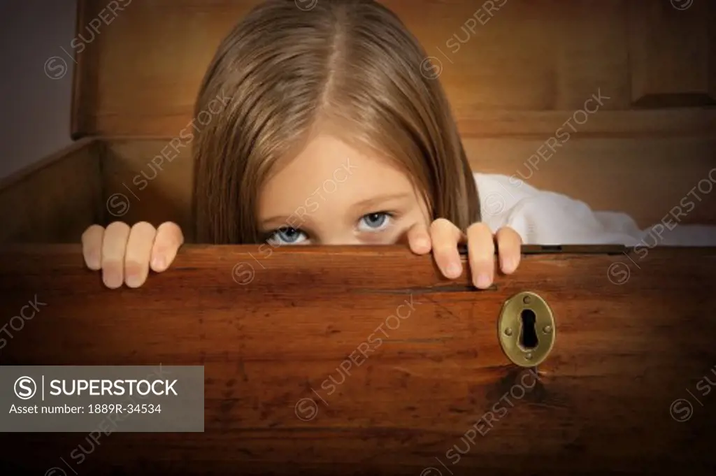 Child hiding inside old trunk with key hole  