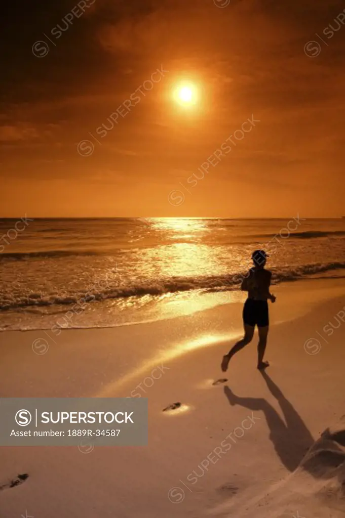 Silhouette of a female jogger along the ocean