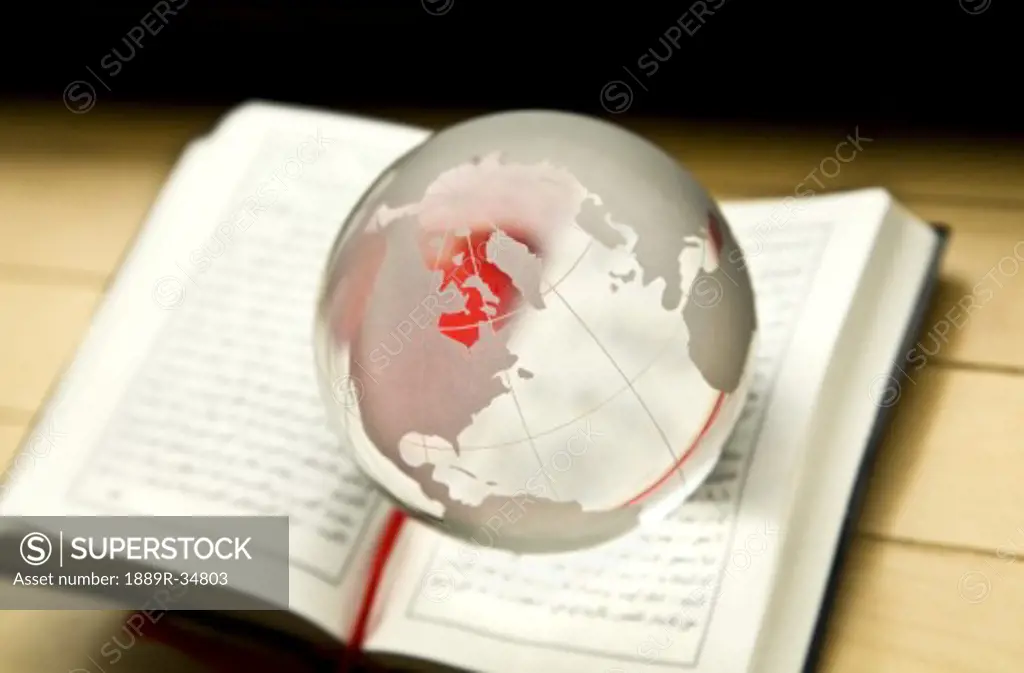 Globe with Middle East facing hovering over the New Testament written in Arabic