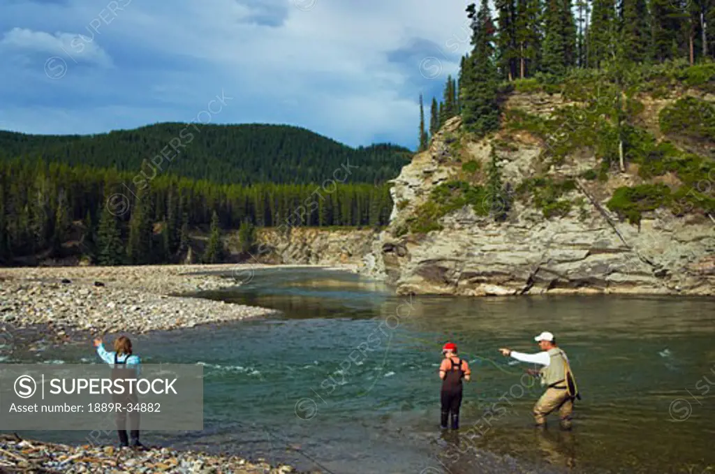 Father and sons fly fishing in a river  