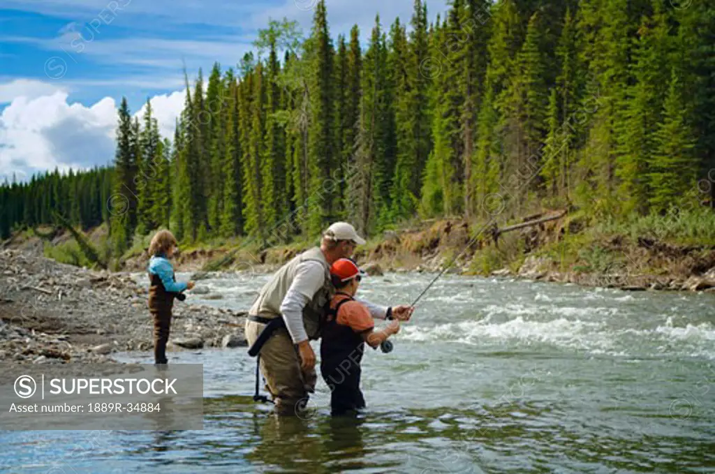 Father and sons fly fishing in a mountain river, Nordegg, Alberta, Canada  