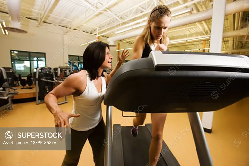 Woman running on treadmill with strong encouragement from trainer