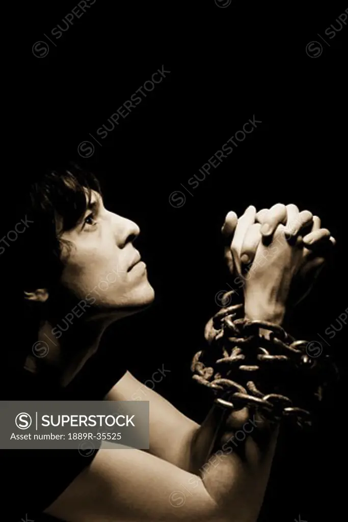 Man in chains with hands clasped