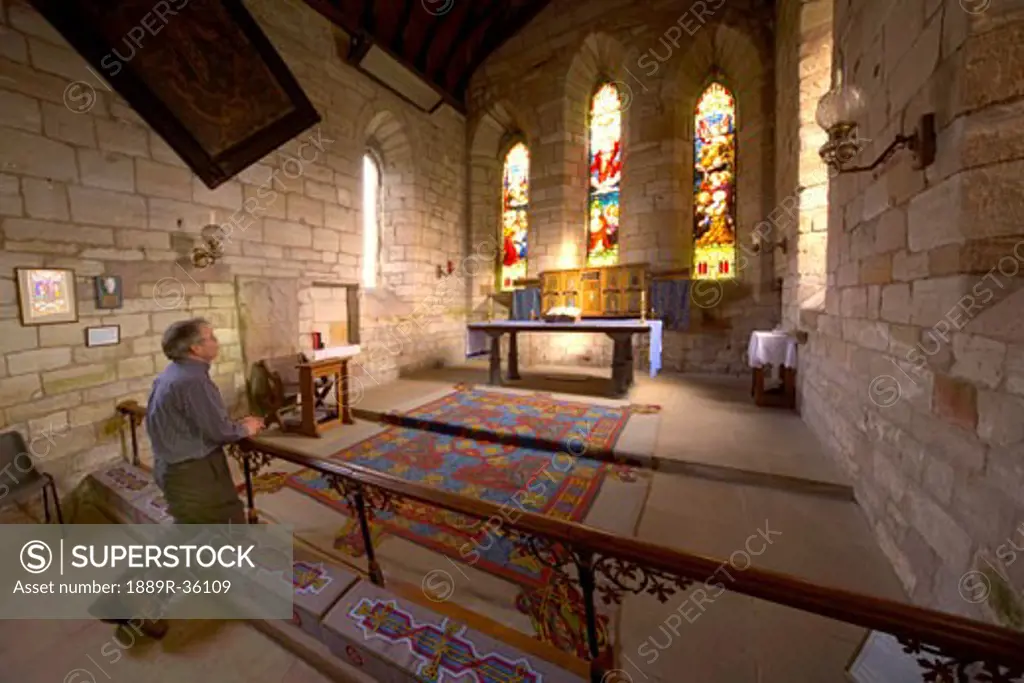 Man praying in chapel, Holy Island, Bewick, England