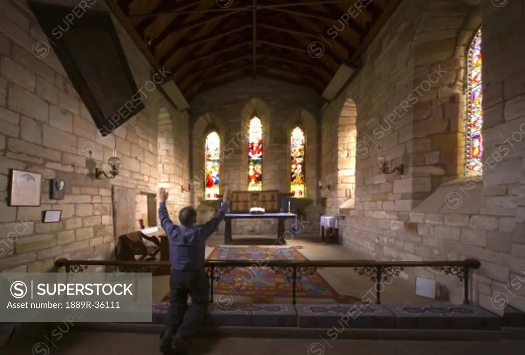 Man praying in chapel, Holy Island, Bewick, England