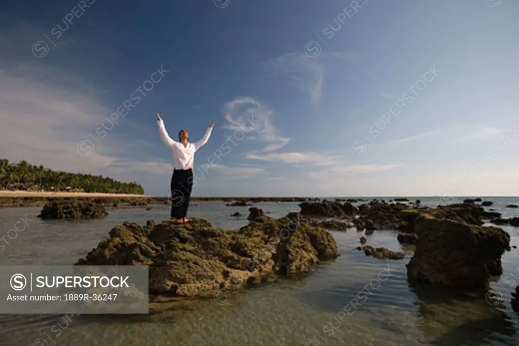 A man on a rock with arms outstretched