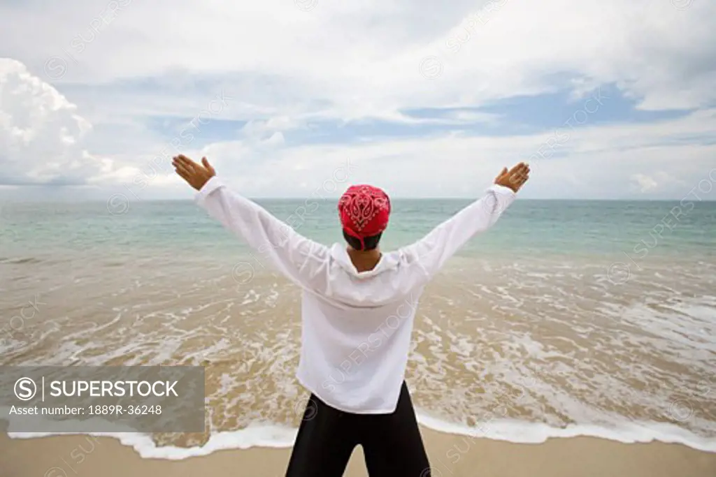A man with arms outstretched on a beach in Koh Lanta, Thailand
