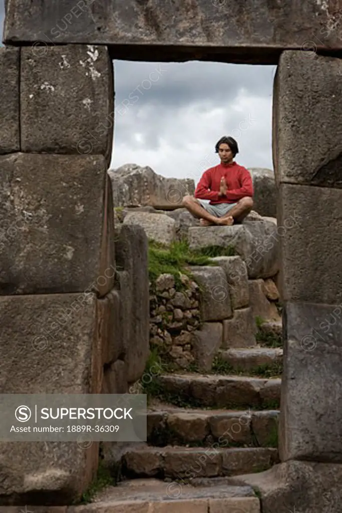 A young man meditates in ancient Incan ruins outside Cuzco, Peru