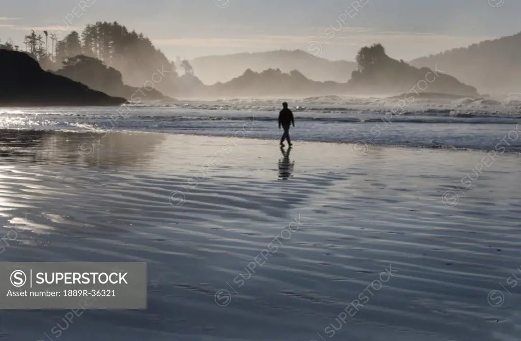 A man walking along Chesterman's Beach near Tofino on Vancouver Island, British Columbia, Canada