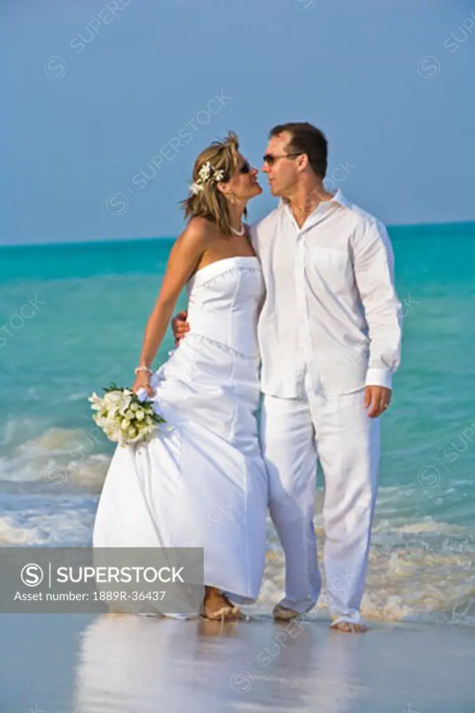 Bride and groom embracing on beach