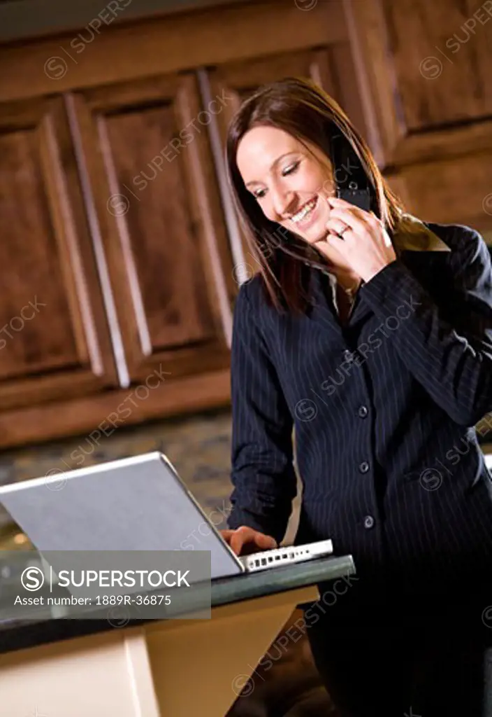 Businesswoman using a cell phone and a laptop