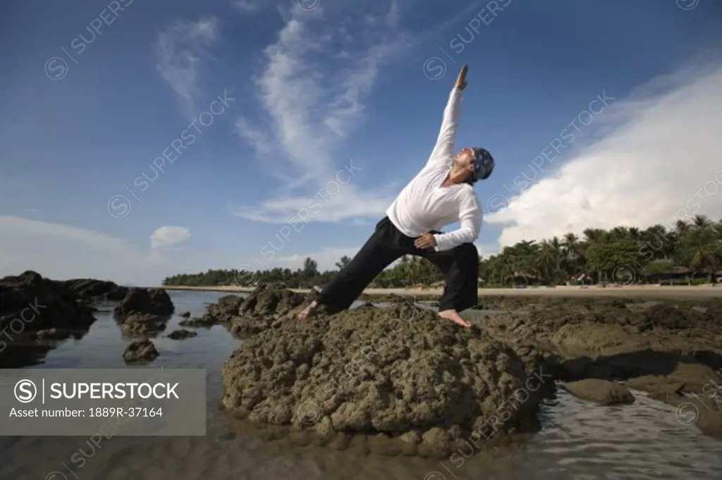 A man stretching on a rocky beach in Koh Lanta, Thailand