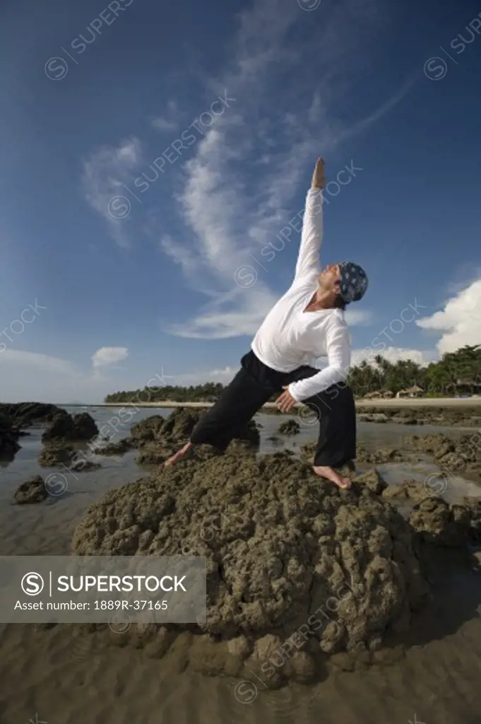 A man stretching on a rocky beach in Koh Lanta, Thailand