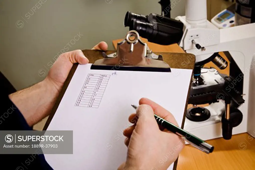 A Doctor Recording Blood Results On A Clipboard