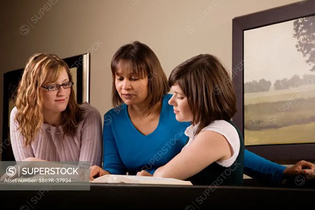 Three women discussing a book