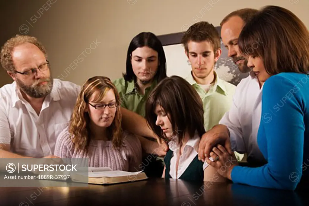 A Group Crowded Around A Bible