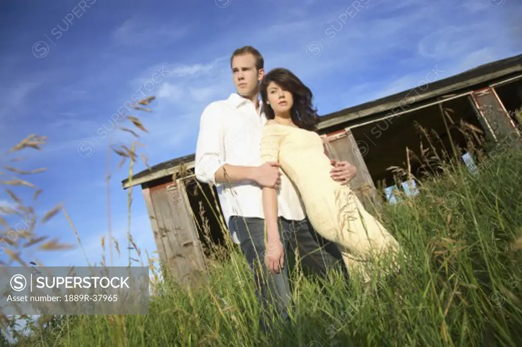 A Young Couple Standing In Front Of A Shack