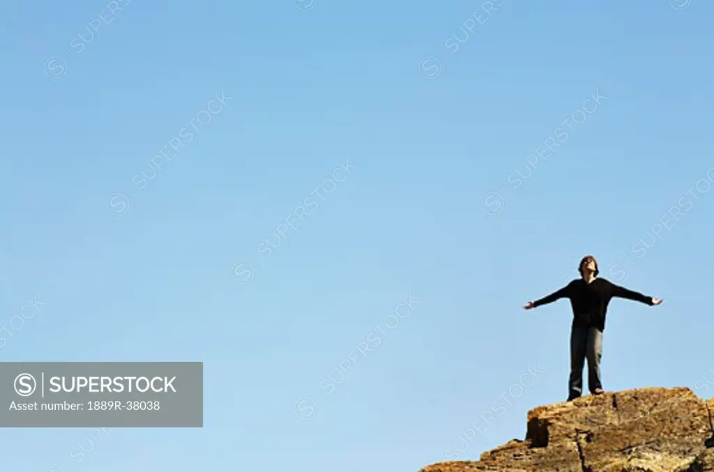 Man Standing On The Edge Of A Cliff With His Arms Outstretched