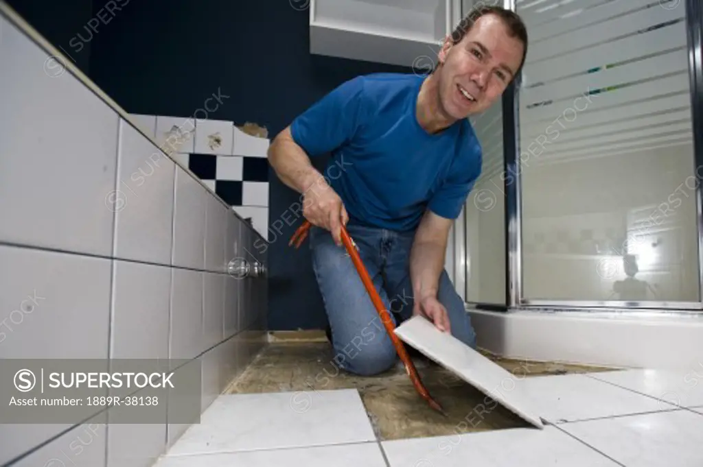Man installing bathroom floor tiles