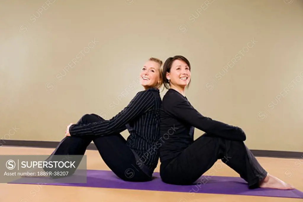 Two women sitting back to back