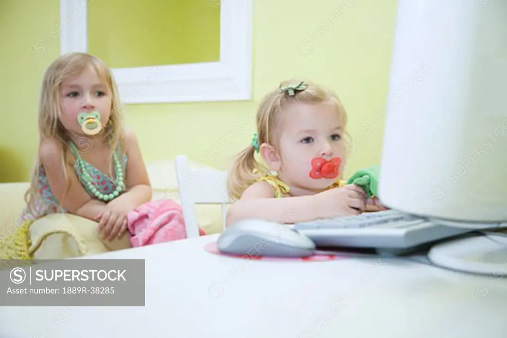 Two girls with soothers at computer