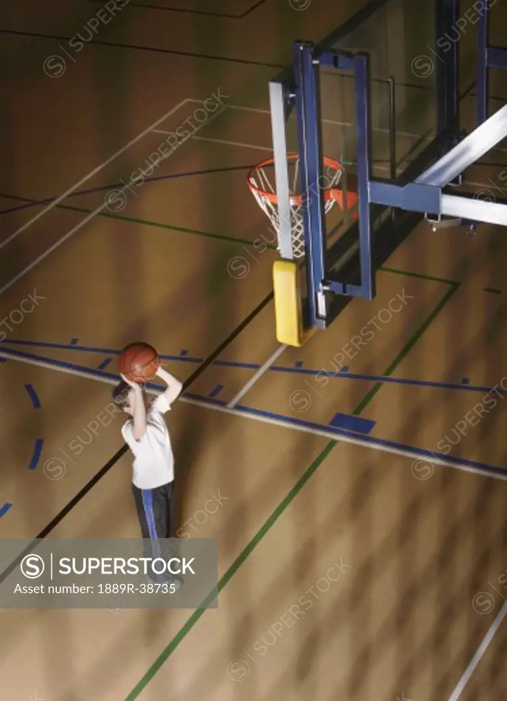Boy aiming ball at basketball net