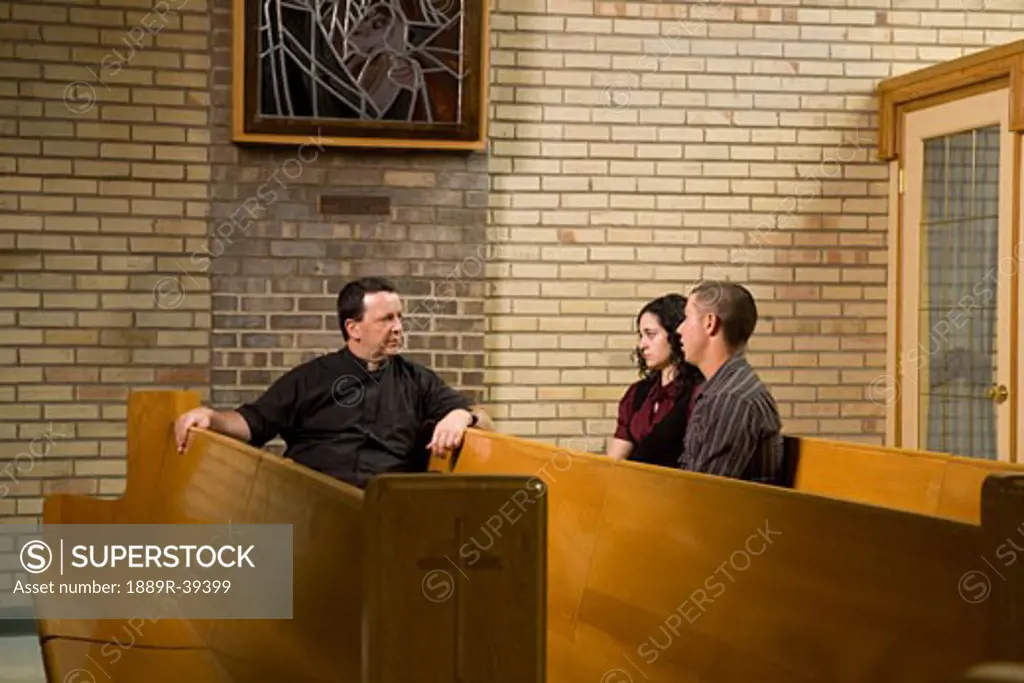 Catholic Priest talking with a young couple