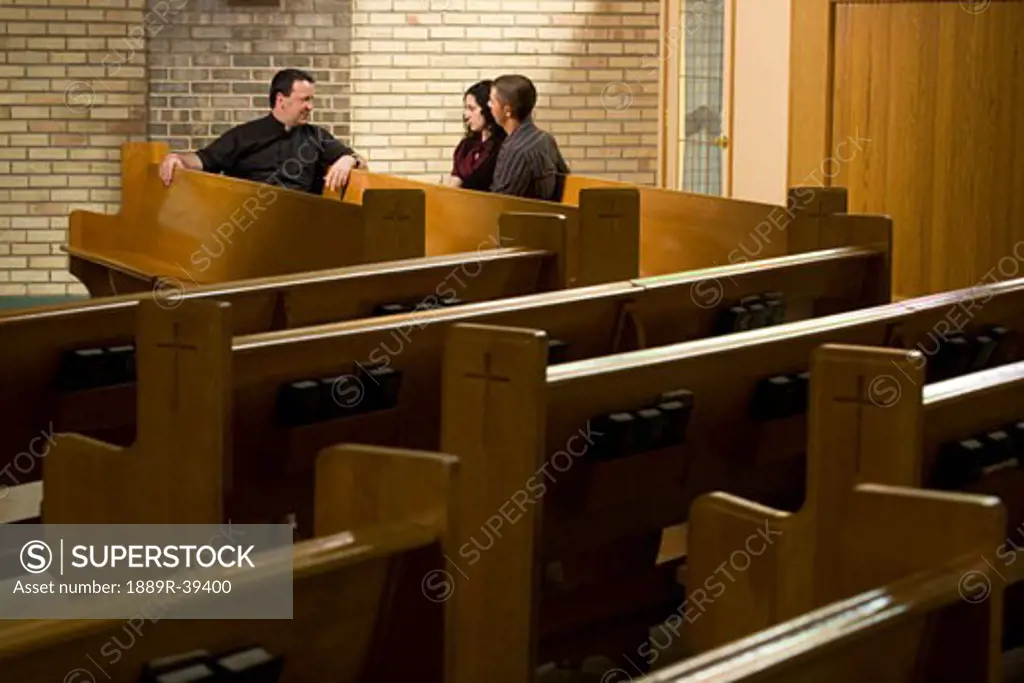Catholic Priest talking with a couple in a church