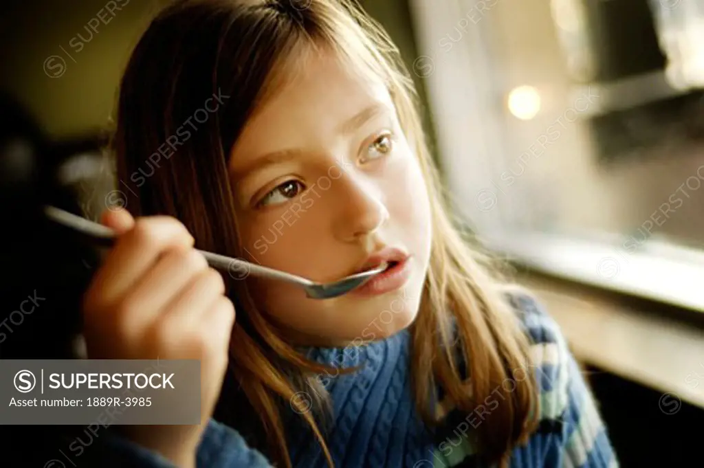 Young girl with spoon to mouth