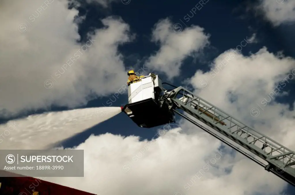Firemen in ladder spraying water